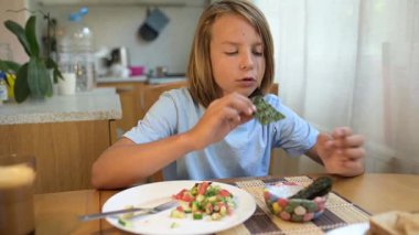 Küçük bir çocuk kahvaltı masasında yosun yiyor. Doğal ışık ve rahat ev atmosferiyle sağlıklı bir sabah rutini..