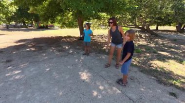 Aile parkta birlikte petanque oynuyor. Yetişkinler ve çocuklar güneşli bir yaz gününde sırayla metal toplar atıyorlar. Eğlenceli bir açık hava aktivitesi ve aile bağları oyunu.