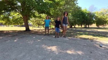 Aile parkta birlikte petanque oynuyor. Yetişkinler ve çocuklar güneşli bir yaz gününde sırayla metal toplar atıyorlar. Eğlenceli bir açık hava aktivitesi ve aile bağları oyunu.