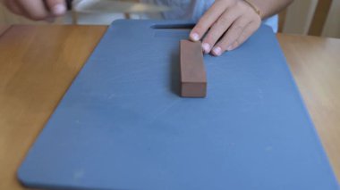 Evdeki bileytaşı üzerinde bıçak keskinleştiren ellerin yakın çekimi. Mutfak güvenliği, yemek hazırlığı, bileme aletleri, ev işleri ve pratik beceriler kavramı.