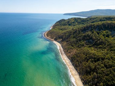 Aerial view of wild Bulgarian coastline with turquoise sea and green forested cliffs, scenic untouched nature and beautiful seascape.