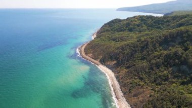 Aerial view of wild Bulgarian coastline with turquoise sea and green forested cliffs, scenic untouched nature and beautiful seascape.