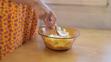 Pouring dough mixture into a bowl of flour, close up of baking process at home kitchen, cooking ingredients being combined for homemade recipe.