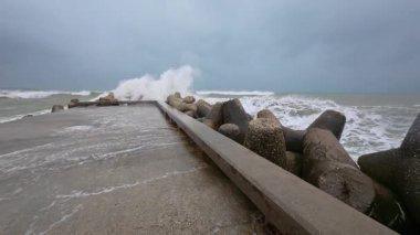 Powerful storm waves crashing against a pier in slow motion, first-person view of dramatic ocean spray and rough sea.