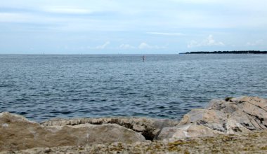 Kürek çeken adam ayağa kalktı. Kürek tahtası ve mavi deniz manzarası