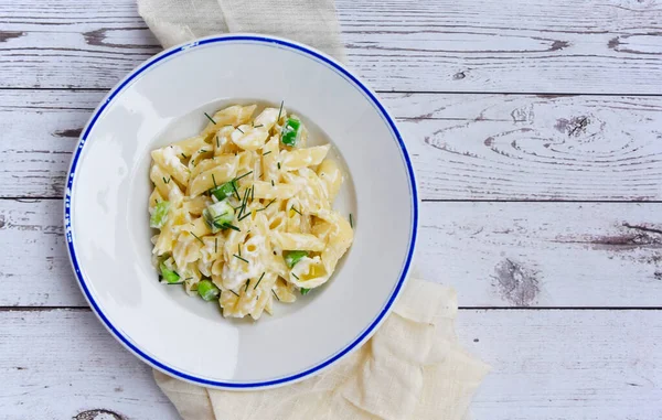 stock image Plate of pasta with cream cheese and herbs. Cheese sauce pasta served on wooden table