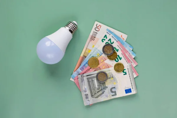 stock image Energy saving. LED light bulbs and money on green background, flat lay