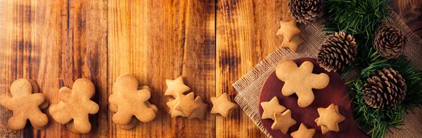 Homemade gingerbread men cookies and star shaped cookies, traditionally made at Christmas and the holidays. Table top view panoramic image.