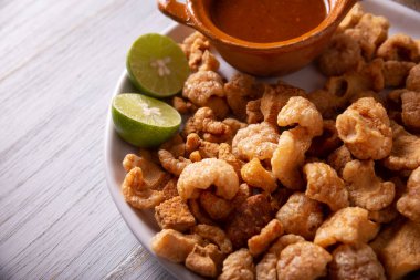 Chicharronelar. Kızarmış domuz derisi, kızarmış domuz derisi, geleneksel Meksika malzemesi ya da limon suyu ve kırmızı acı biber sosuyla servis edilen aperatif..