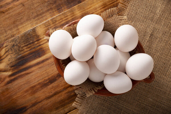 Many white chicken eggs on rustic wooden table. Very popular nutritious and economic food product. Table top view.