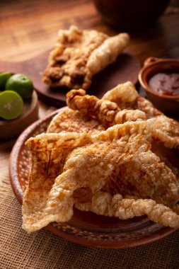 Chicharron. Kızarmış domuz derisi, havalanmış ve kızarmış domuz derisi, geleneksel Meksika malzemesi ya da limon suyu ve kırmızı acı sosla servis edilen aperatif..
