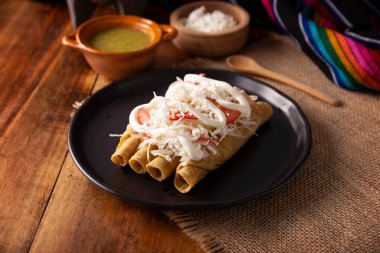 Tacos Dorados. Flautas olarak da bilinen Meksika yemeği, dolgulu mısır tortillasından oluşur, yaygın olarak tavuk veya sığır eti veya patates gibi vejetaryen seçenekleri içerir..