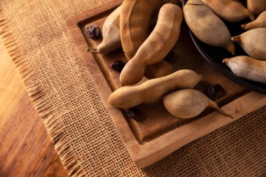 Tamarind fruit (Tamarindus indica) on wooden rustic table. Tropical fruit highly appreciated in several countries of the world. Closeup image.