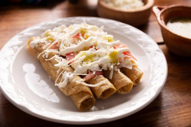 Tacos Dorados. Flautas olarak da bilinen Meksika yemeği, dolgulu mısır tortillasından oluşur, yaygın olarak tavuk veya sığır eti veya patates gibi vejetaryen seçenekleri içerir..