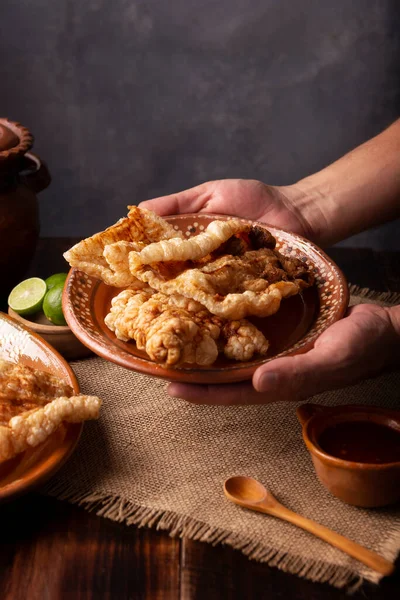 stock image Chicharron. Crispy Fried pork rind, are pieces of aired and fried pork skin, traditional Mexican ingredient or snack served with lime juice and red hot sauce.