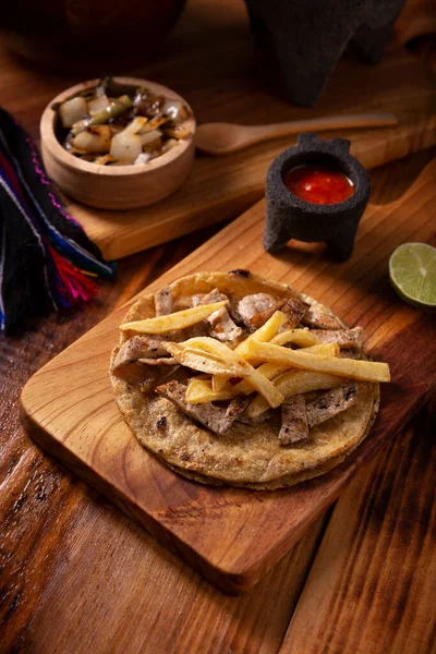 Beef steak taco with french fries. Very popular taco in Mexico called Taco de Bistec, homemade roast beef served on a corn tortilla. Mexican street food.