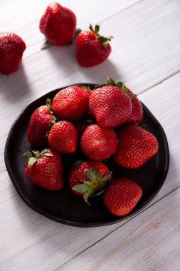 Tahta masada taze organik çilekler (fragaria). Bazı İspanyolca konuşan ülkelerde Frutilla olarak da bilinir, tek başına yenen bir orman meyvesidir..