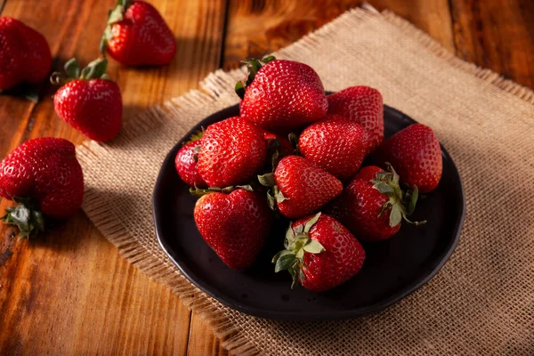 Tahta masada taze organik çilekler (fragaria). Bazı İspanyolca konuşan ülkelerde Frutilla olarak da bilinir, tek başına yenen bir orman meyvesidir..