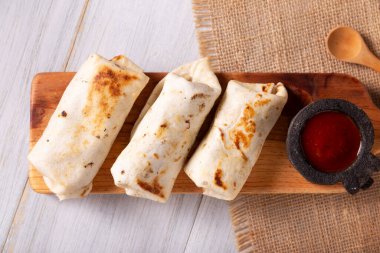 Burritos. Wrapped wheat flour tortilla, can be filled with various ingredients such as scrambled eggs or minced meat, beans and vegetables, a very popular dish in Mexico and the southern USA. clipart