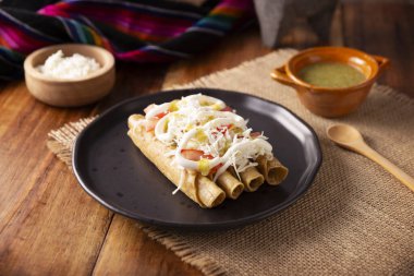 Tacos Dorados. Flautas olarak da bilinen Meksika yemeği, dolgulu mısır tortillasından oluşur, yaygın olarak tavuk veya sığır eti veya patates gibi vejetaryen seçenekleri içerir..