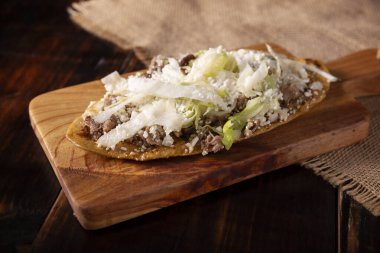 Huarache (yemek). Mısır hamuru ve fasulyelerden yapılmış tipik Meksika oval yemekleri, genellikle marul, peynir, sos ve biftek, kaburga ya da yumurta gibi proteinlerle kaplıdır..