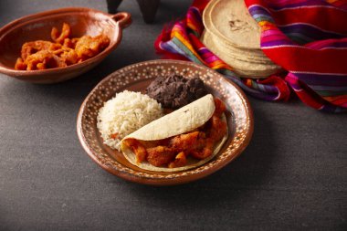 Chicharron en salsa roja. Yanında pilav ve kızarmış fasulye ile birlikte kırmızı soslu domuz derisi. Geleneksel ev yemeği Meksika 'da çok popüler, bu yemek popüler Tacos de Guisado' nun bir parçası..