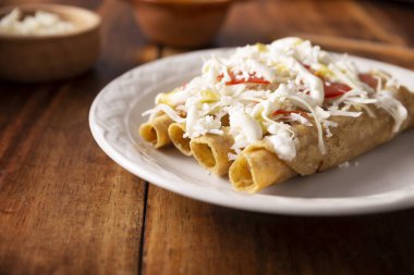 Tacos Dorados. Flautas olarak da bilinen Meksika yemeği, dolgulu mısır tortillasından oluşur, yaygın olarak tavuk veya sığır eti veya patates gibi vejetaryen seçenekleri içerir..