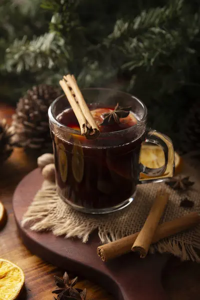 Spiced wine or Christmas mulled wine with orange, cinnamon, star anise, clove, nutmeg and other ingredients on a wooden rustic table. Traditional hot drink at winter time and Christmas holidays.