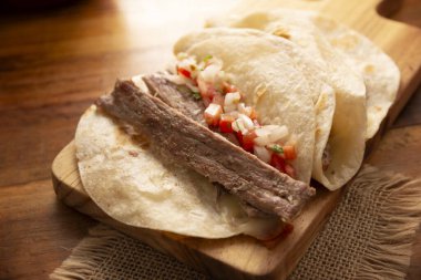 Tacos de Arrachera 'da. Buğday tortillasında ev yapımı ızgara et. Meksika 'dan gelen sokak yemekleri, geleneksel olarak kişniş, soğan ve baharatlı sos ya da guacamole ile birlikte..