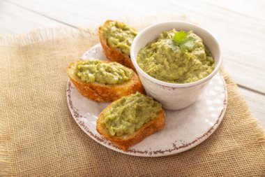 Avokado tostu ezilmiş. Avokado tostu püresi. Sağlıklı beslenme, diyet, lezzetli vejetaryen yemekleri. Beyaz tabakta servis edilmiş. Sağlıklı ev yapımı kahvaltı için kolay tarif.