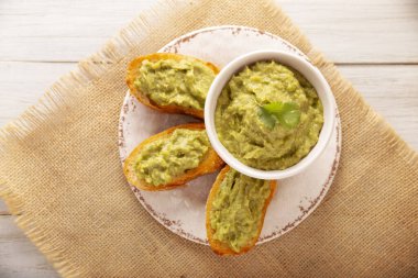 Avokado tostu ezilmiş. Avokado tostu püresi. Sağlıklı beslenme, diyet, lezzetli vejetaryen yemekleri. Beyaz tabakta servis edilmiş. Sağlıklı ev yapımı kahvaltı için kolay tarif.