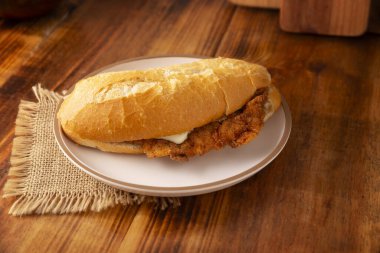 Meksikalı Torta de Milanesa. Bolillo ekmeği, telera ya da baget ekmeği ile yapılmış sandviç, ikiye bölünmüş ve çeşitli malzemelerle doldurulmuş, bu durumda Oaxaca peynirli tavuk eti..