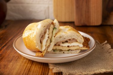 Meksikalı Torta de Milanesa. Bolillo ekmeği, telera ya da baget ekmeği ile yapılmış sandviç, ikiye bölünmüş ve çeşitli malzemelerle doldurulmuş, bu durumda Oaxaca peynirli tavuk eti..