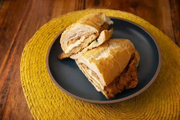 Meksikalı Torta de Milanesa. Bolillo ekmeği, telera ya da baget ekmeği ile yapılmış sandviç, ikiye bölünmüş ve çeşitli malzemelerle doldurulmuş, bu durumda Oaxaca peynirli tavuk eti..