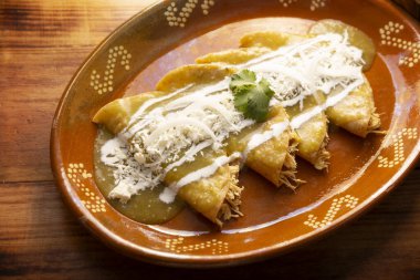 Yeşil enchilada. Tipik Meksika yemeği, doğranmış tavukla doldurulmuş ve baharatlı yeşil sos, krem, rendelenmiş peynir ve soğanla kaplı katlanmış veya sarılmış mısır tortillasıyla yapılır..