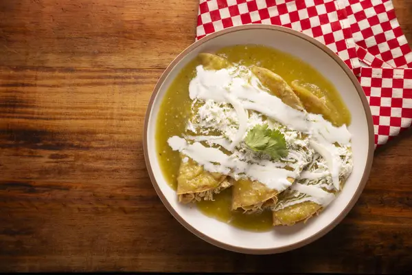 Yeşil enchilada. Tipik Meksika yemeği, doğranmış tavukla doldurulmuş ve baharatlı yeşil sos, krem, rendelenmiş peynir ve soğanla kaplı katlanmış veya sarılmış mısır tortillasıyla yapılır..