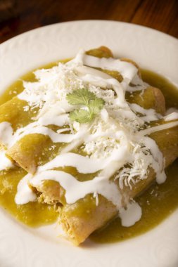 Yeşil enchilada. Tipik Meksika yemeği, doğranmış tavukla doldurulmuş ve baharatlı yeşil sos, krem, rendelenmiş peynir ve soğanla kaplı katlanmış veya sarılmış mısır tortillasıyla yapılır..