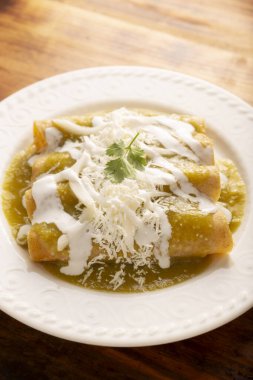 Yeşil enchilada. Tipik Meksika yemeği, doğranmış tavukla doldurulmuş ve baharatlı yeşil sos, krem, rendelenmiş peynir ve soğanla kaplı katlanmış veya sarılmış mısır tortillasıyla yapılır..