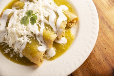 Yeşil enchilada. Tipik Meksika yemeği, doğranmış tavukla doldurulmuş ve baharatlı yeşil sos, krem, rendelenmiş peynir ve soğanla kaplı katlanmış veya sarılmış mısır tortillasıyla yapılır..