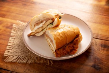 Meksikalı Torta de Milanesa. Bolillo ekmeği, telera ya da baget ekmeği ile yapılmış sandviç, ikiye bölünmüş ve çeşitli malzemelerle doldurulmuş, bu durumda Oaxaca peynirli tavuk eti..