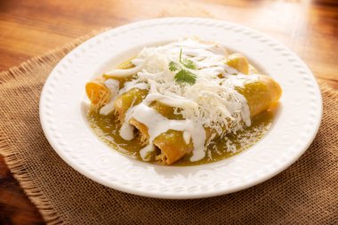 Yeşil enchilada. Tipik Meksika yemeği, doğranmış tavukla doldurulmuş ve baharatlı yeşil sos, krem, rendelenmiş peynir ve soğanla kaplı katlanmış veya sarılmış mısır tortillasıyla yapılır..