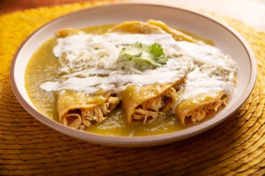 Yeşil enchilada. Tipik Meksika yemeği, doğranmış tavukla doldurulmuş ve baharatlı yeşil sos, krem, rendelenmiş peynir ve soğanla kaplı katlanmış veya sarılmış mısır tortillasıyla yapılır..