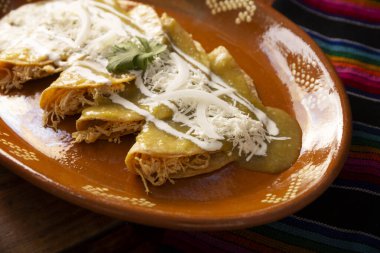 Yeşil enchilada. Tipik Meksika yemeği, doğranmış tavukla doldurulmuş ve baharatlı yeşil sos, krem, rendelenmiş peynir ve soğanla kaplı katlanmış veya sarılmış mısır tortillasıyla yapılır..