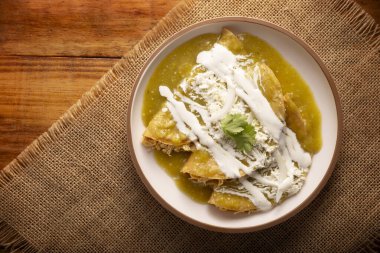 Yeşil enchilada. Tipik Meksika yemeği, doğranmış tavukla doldurulmuş ve baharatlı yeşil sos, krem, rendelenmiş peynir ve soğanla kaplı katlanmış veya sarılmış mısır tortillasıyla yapılır..