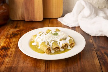 Yeşil enchilada. Tipik Meksika yemeği, doğranmış tavukla doldurulmuş ve baharatlı yeşil sos, krem, rendelenmiş peynir ve soğanla kaplı katlanmış veya sarılmış mısır tortillasıyla yapılır..