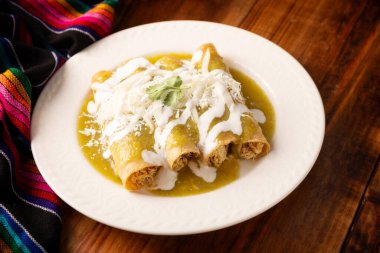 Yeşil enchilada. Tipik Meksika yemeği, doğranmış tavukla doldurulmuş ve baharatlı yeşil sos, krem, rendelenmiş peynir ve soğanla kaplı katlanmış veya sarılmış mısır tortillasıyla yapılır..