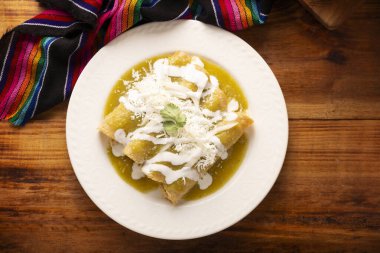 Yeşil enchilada. Tipik Meksika yemeği, doğranmış tavukla doldurulmuş ve baharatlı yeşil sos, krem, rendelenmiş peynir ve soğanla kaplı katlanmış veya sarılmış mısır tortillasıyla yapılır..
