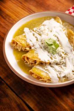 Yeşil enchilada. Tipik Meksika yemeği, doğranmış tavukla doldurulmuş ve baharatlı yeşil sos, krem, rendelenmiş peynir ve soğanla kaplı katlanmış veya sarılmış mısır tortillasıyla yapılır..