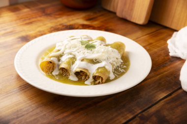 Yeşil enchilada. Tipik Meksika yemeği, doğranmış tavukla doldurulmuş ve baharatlı yeşil sos, krem, rendelenmiş peynir ve soğanla kaplı katlanmış veya sarılmış mısır tortillasıyla yapılır..