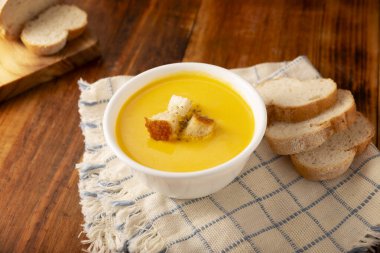 Ev yapımı havuç ve balkabağı kremalı çorba. Kolay, besleyici ve sağlıklı bir tarif. Ekmek kırıntılarıyla birlikte beyaz bir kasede servis edilmiş. Günlük yemek için mükemmel..